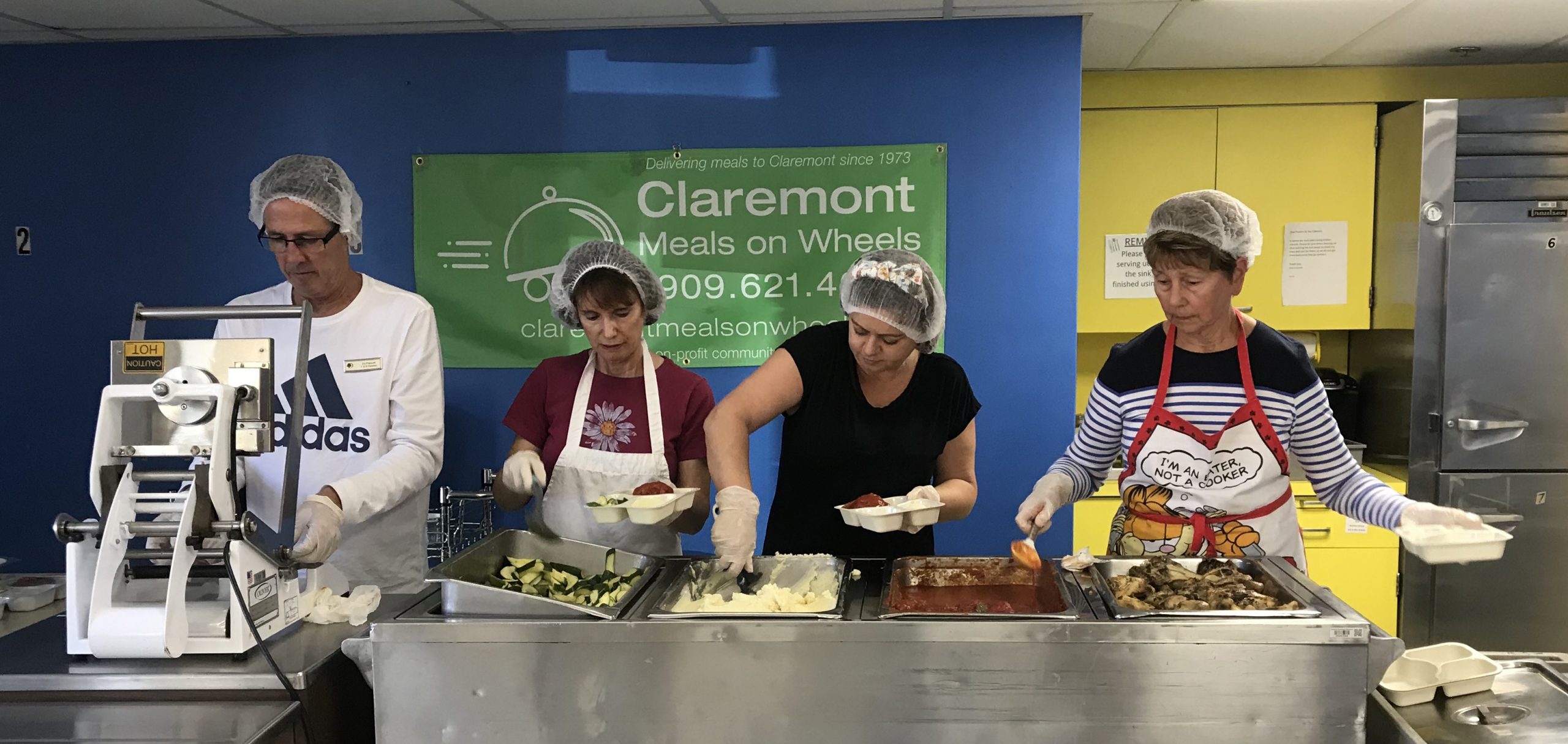 Volunteers serving meat, potatoes, and vegetables